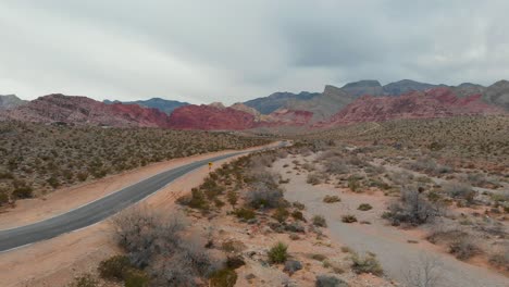 Aerial-drone-shot-of-an-empty-desert-road-with-scenic-mountains-in-the-background