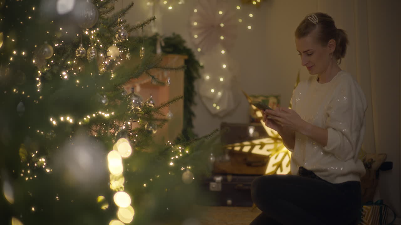 mujer tomando una foto de un árbol de navidad