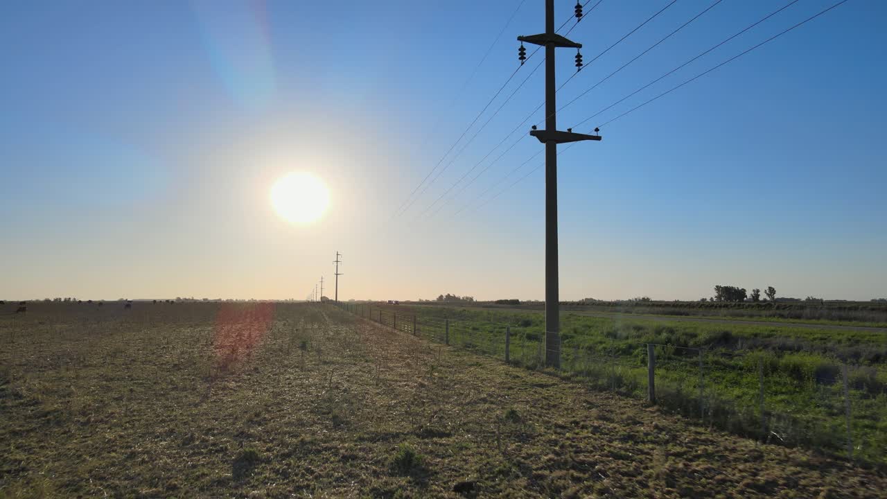 antena hacia atrás de líneas eléctricas, automóviles y campos en la pampa, argentina.