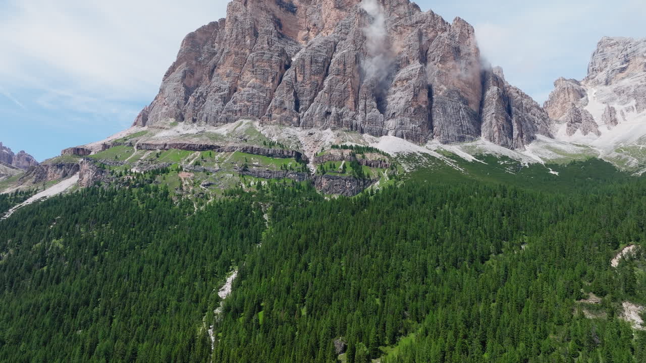 Scenic aerial ascend of Cinque Torri rock formations rising above alpine terrain in Dolomites