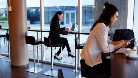 mujeres ejecutivas que usan portátiles y teléfonos móviles