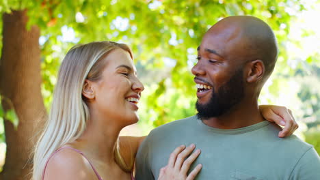 retrato de una pareja amorosa de varias razas de pie al aire libre en un parque de jardín o en el campo