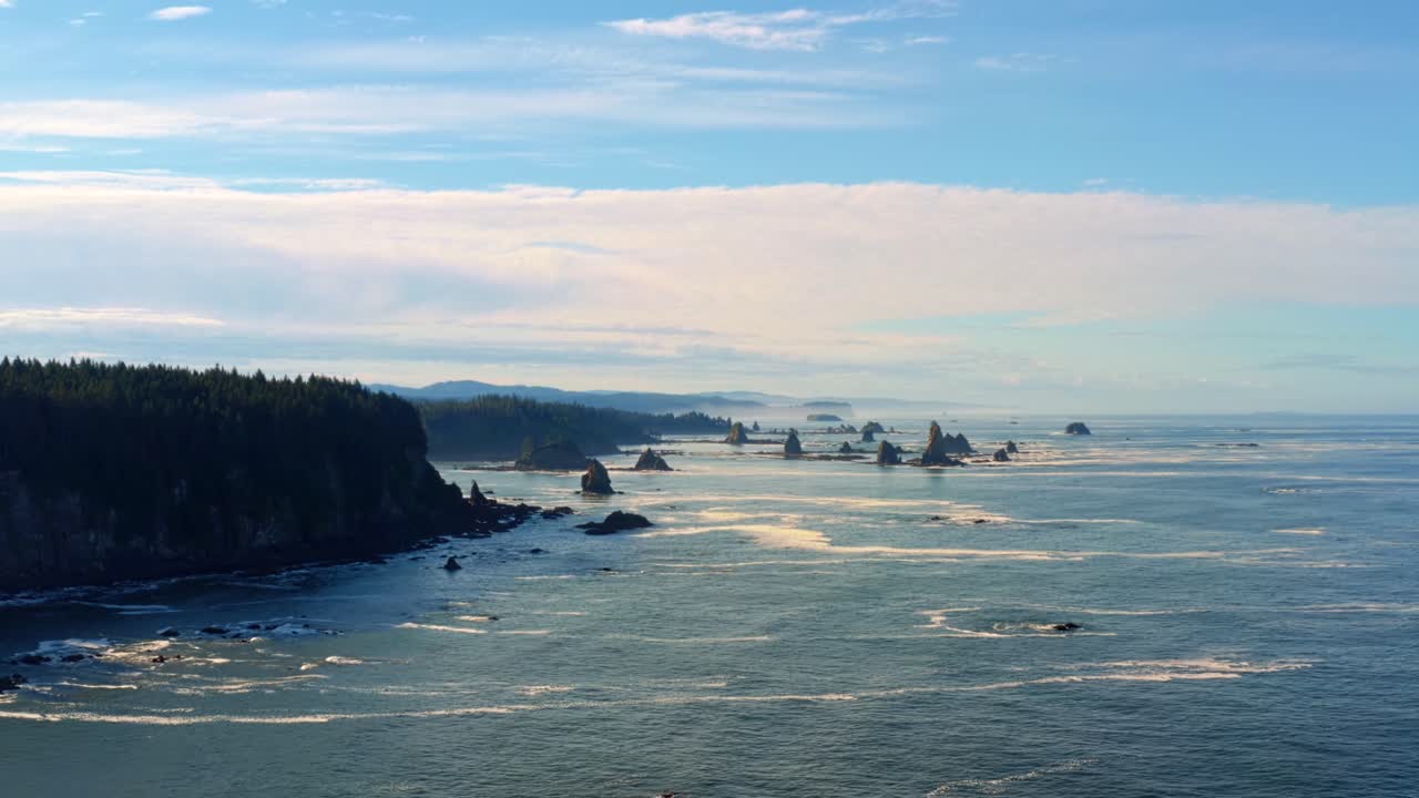 Stunning aerial drone dolly in shot of the gorgeous Third Beach in Forks, Washington with large rock formations, cliffs, small waves and sea foam on a warm sunny summer morning