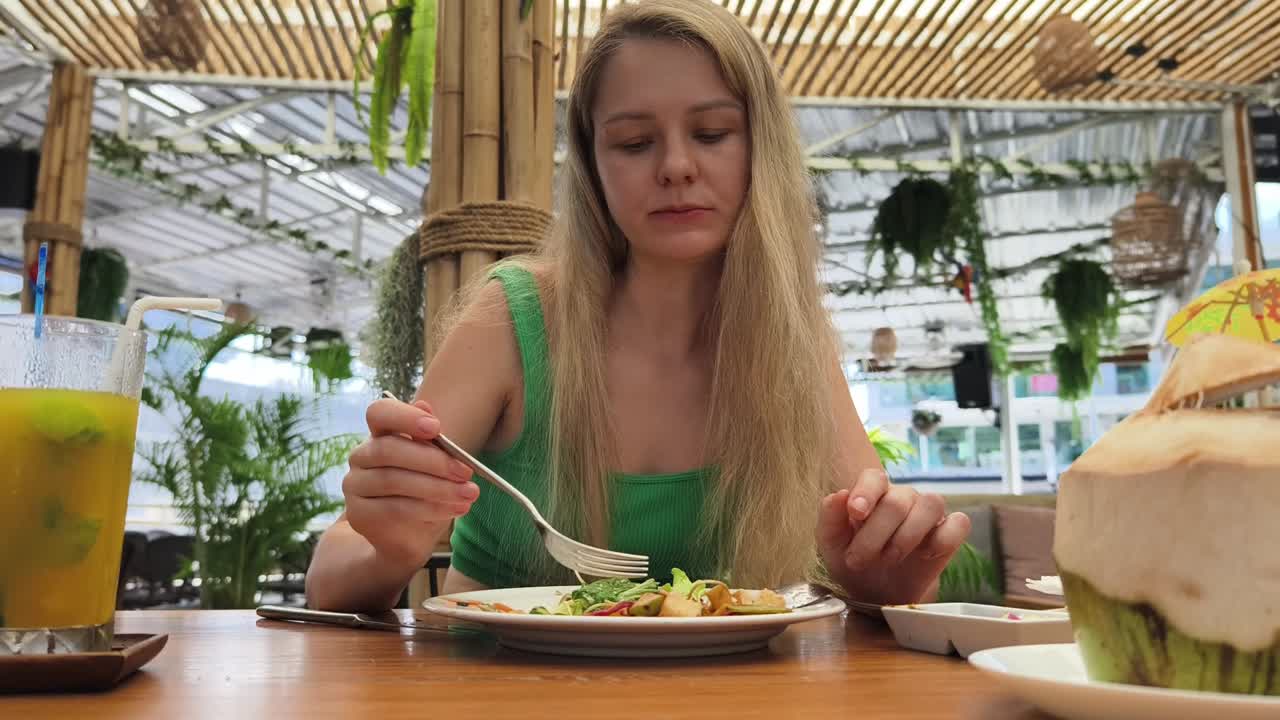 mujer comiendo ensalada en un restaurante tropical