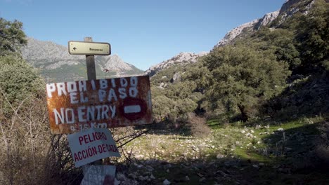 Handwritten-NO-ENTRY-hunting-sign-in-English-and-Spanish-in-forest,-Pan-Left