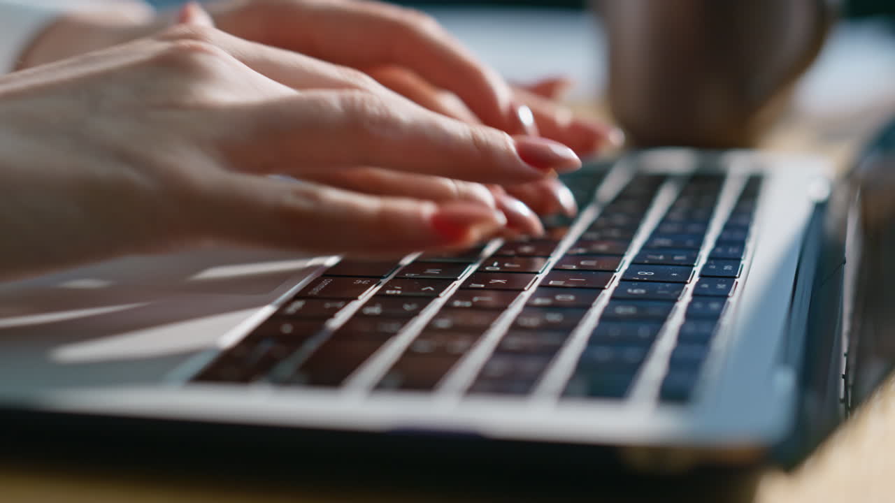 Businesswoman hands writing email on laptop sitting sunlit workplace closeup