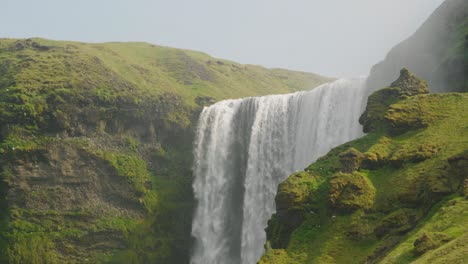 majestic skogafoss waterfall in iceland, beautiful sunny day with birds flying above the mossy cliffs and rocks