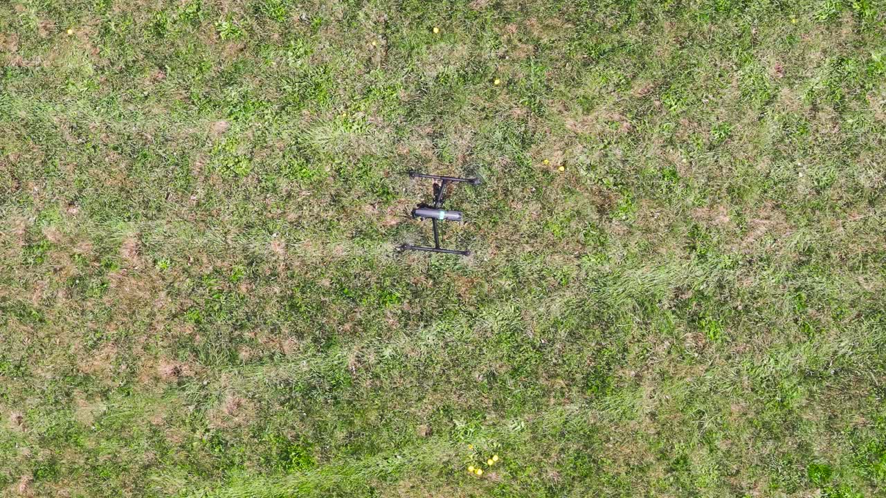 Top down view of advanced filmmaking drone hover above grass field, Czechia