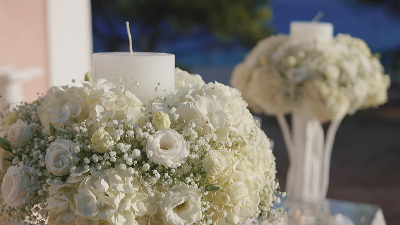 Elegante scena di matrimonio con fiori bianchi e candele al tramonto.