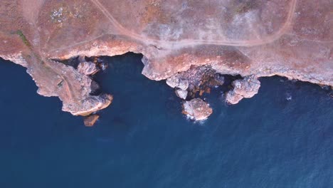 top down aerial view of waves splash against rocky seashore, background