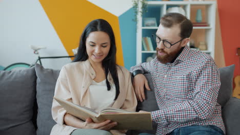 couple looking through photo album on sofa