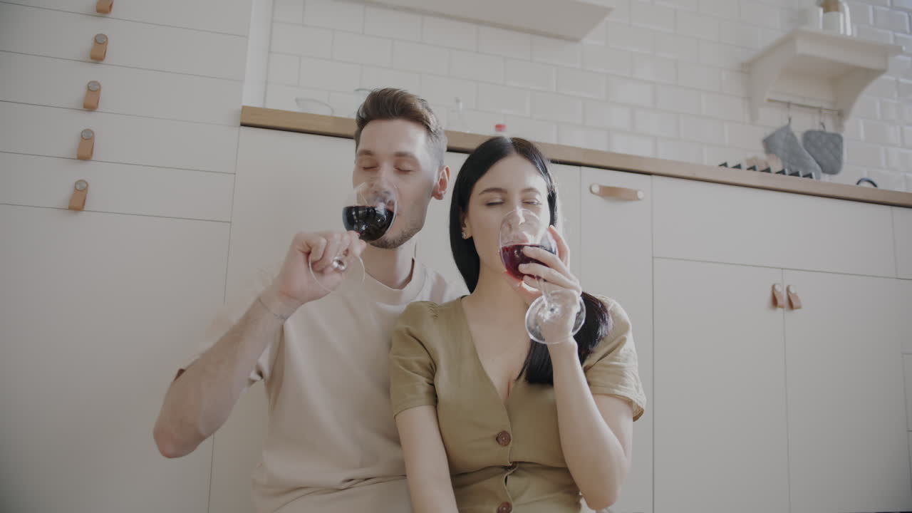 una pareja disfrutando del vino en la cocina.