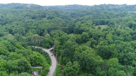 aerial view of a winding road through a lush green forest valley