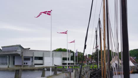 danish flag on flagpole flutter in strong wind near wooden pier, copenhagen