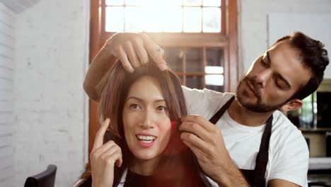 un coiffeur masculin coiffant les cheveux d'une femme