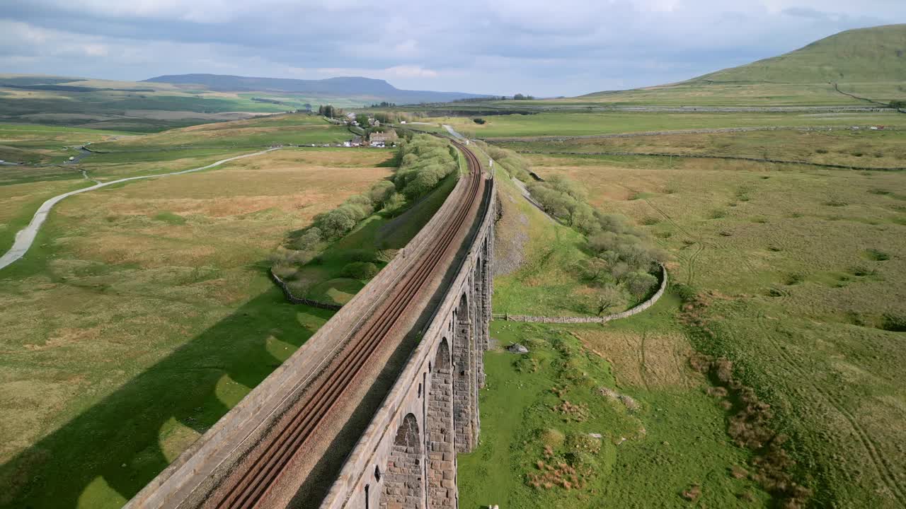 vía ferroviaria curva sobre el puente del viaducto con vuelo inverso del dron revelando la estructura y los arcos en la hora dorada