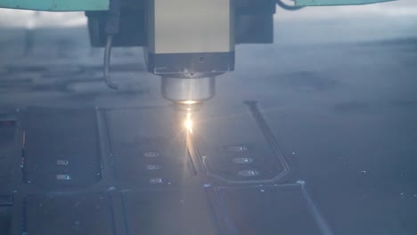 primer plano del corte por láser de chapa metálica con destellos brillantes en la fábrica