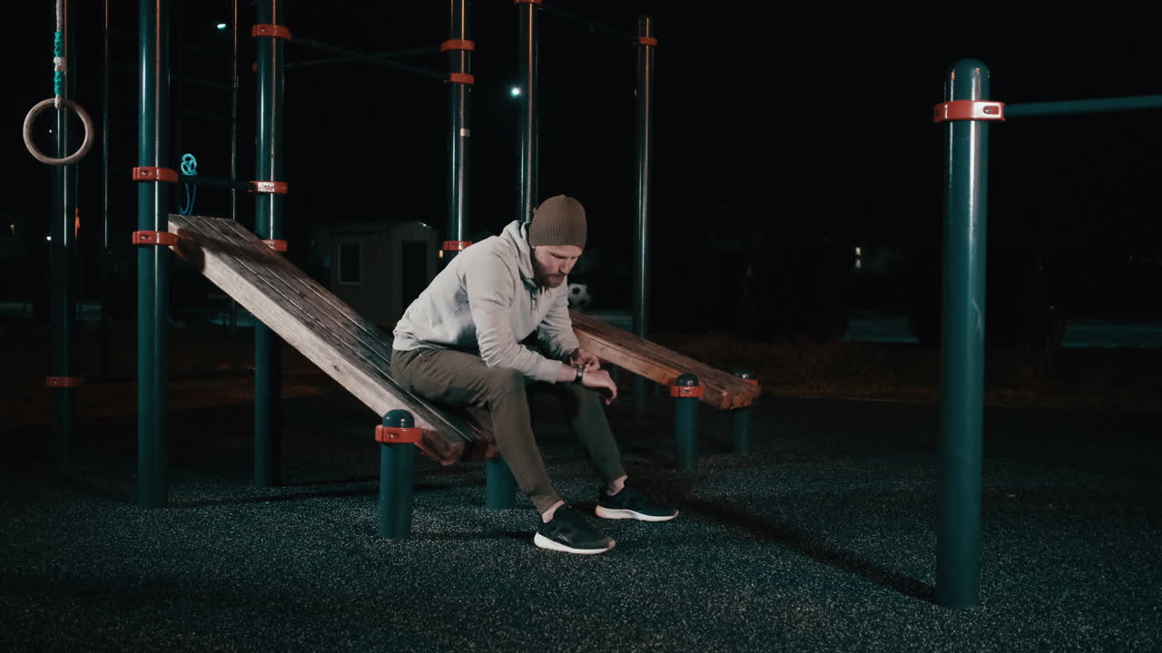 hombre descansando por la noche en un gimnasio al aire libre
