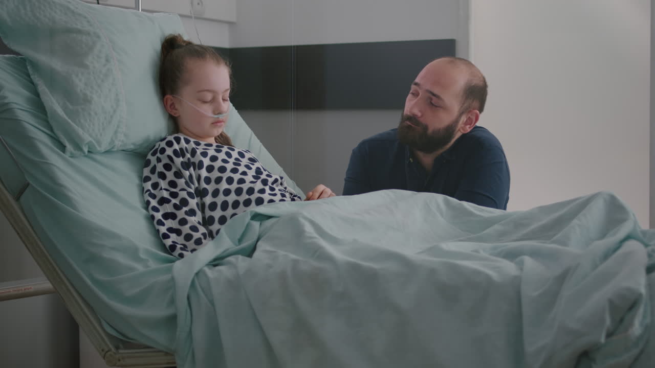 In hospital ward sick girl patient sleeping while worried father praying for sickness recovery