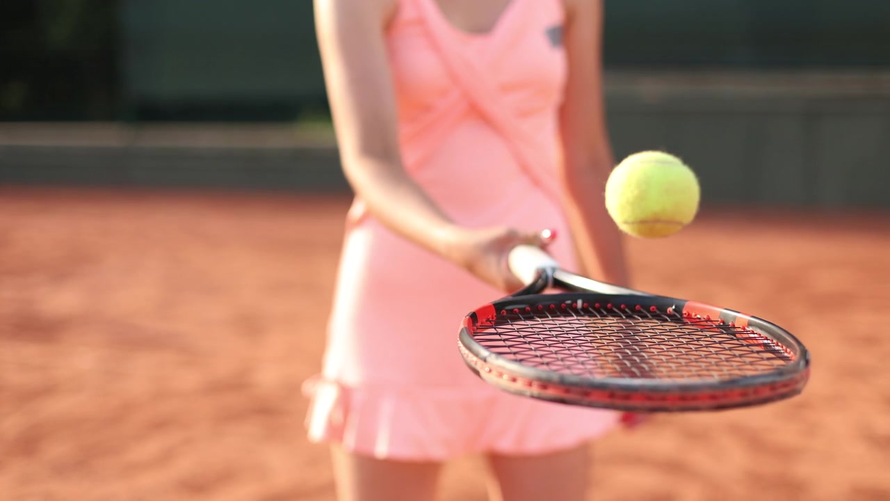 Female Tennis Player Bouncing Ball on Racket on Clay Court