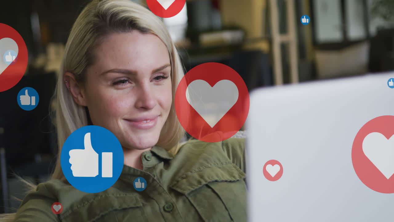 Animation of media icons over smiling caucasian businesswoman using laptop