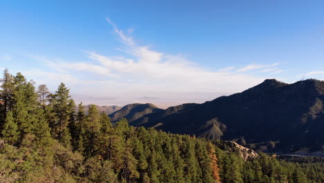 Aerial-of-Rocky-Outcropping-to-Green-Forest-and-Mountain-Range