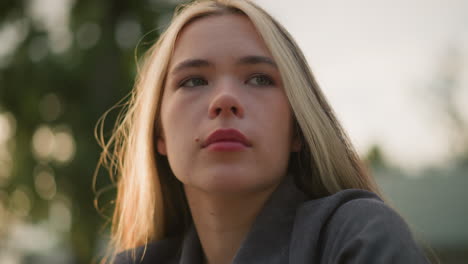 lady in grey shirt gazing into the distance, lost in thought with sunlight creating a warm, serene ambience around her, soft light reflects off her face, with a blurred natural background