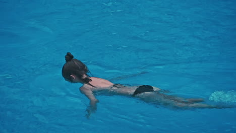 una joven sensual relajándose en la piscina.