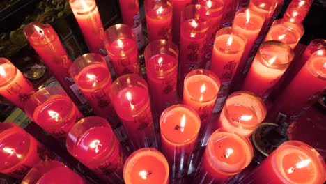 Slow-motion-shot-of-red-candlelights-in-dark-temple-in-Taipei,-Taiwan