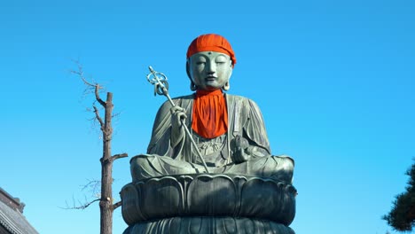 a serene and peaceful scene of a buddha statue outside a traditional japanese temple.