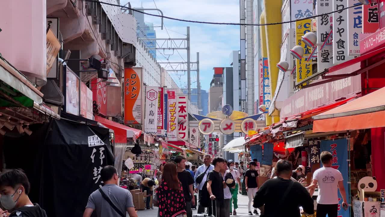Busy Japanese street market with colorful storefronts and people walking under a clear sky