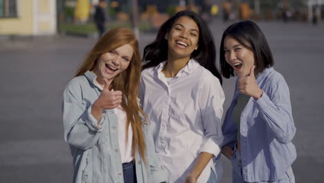 mujeres multiétnicas que muestran el pulgar hacia arriba y el signo de ok juntas al aire libre