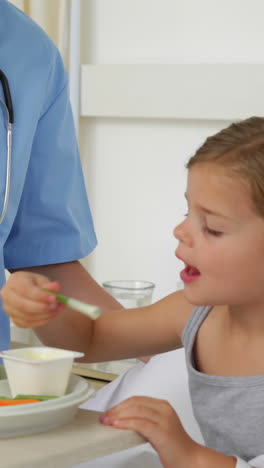 enfermera alimentando a una niña enferma en la cama