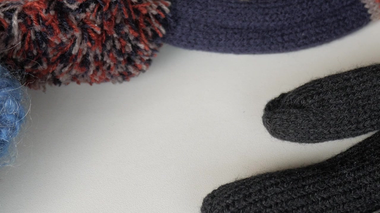 Gorro de inverno de malha colorido com pompom e design da Union Jack em uma superfície branca.