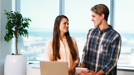 Executives-interacting-while-using-digital-tablet-and-laptop