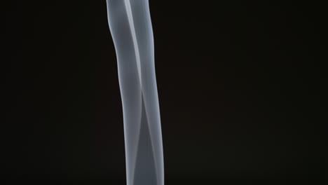 slow motion: elegant vertical line of smoke on a black background