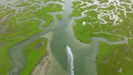 aerial view of a coastal marsh with winding rivers and kiteboarding