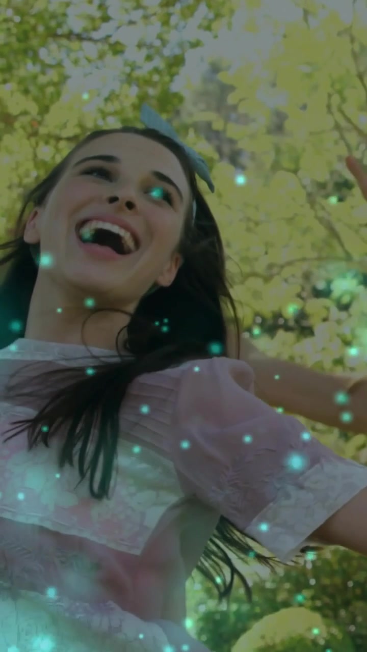 Dikey video: Gülen, dönen, kolları yukarıda bir kadın, arkadaşı reklam için ağaçta dönmesine rehberlik ederken yeşil katman beliriyor