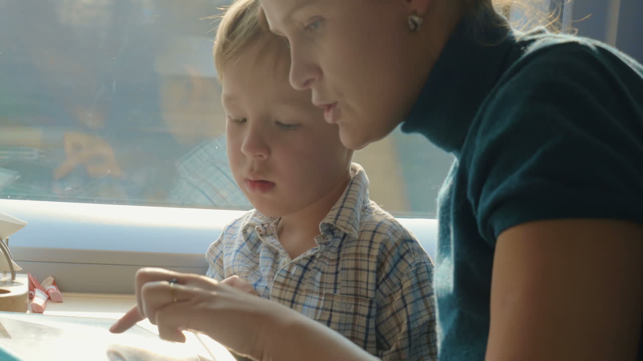 madre e hijo pasando el tiempo en el tren con una tableta