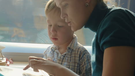 mother and son passing time in train with tablet pc