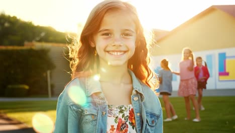 a young girl with red hair smiles happily while standing outdoors in the sun.