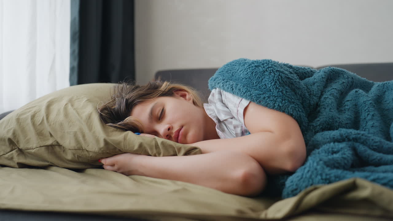 Peaceful Morning Rest, Calm Woman Sleeps Peacefully Indoors, Serene Woman Enjoying Restful Morning Under Soft Blankets, Woman Lies Peacefully On Comfortable Couch During Calm Morning At Home