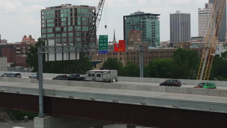 Aerial-view-of-busy-broadway-bridge-with-cars-and-trucks-driving-by,-dolly-out