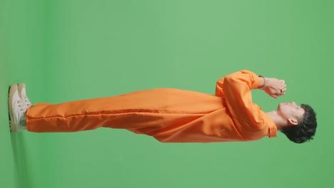vista lateral del cuerpo completo del prisionero masculino asiático en esposas reza por algo mientras está de pie en el fondo de la pantalla verde