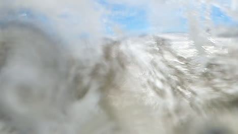 large wave crashes on coastline of green sand beach on camera