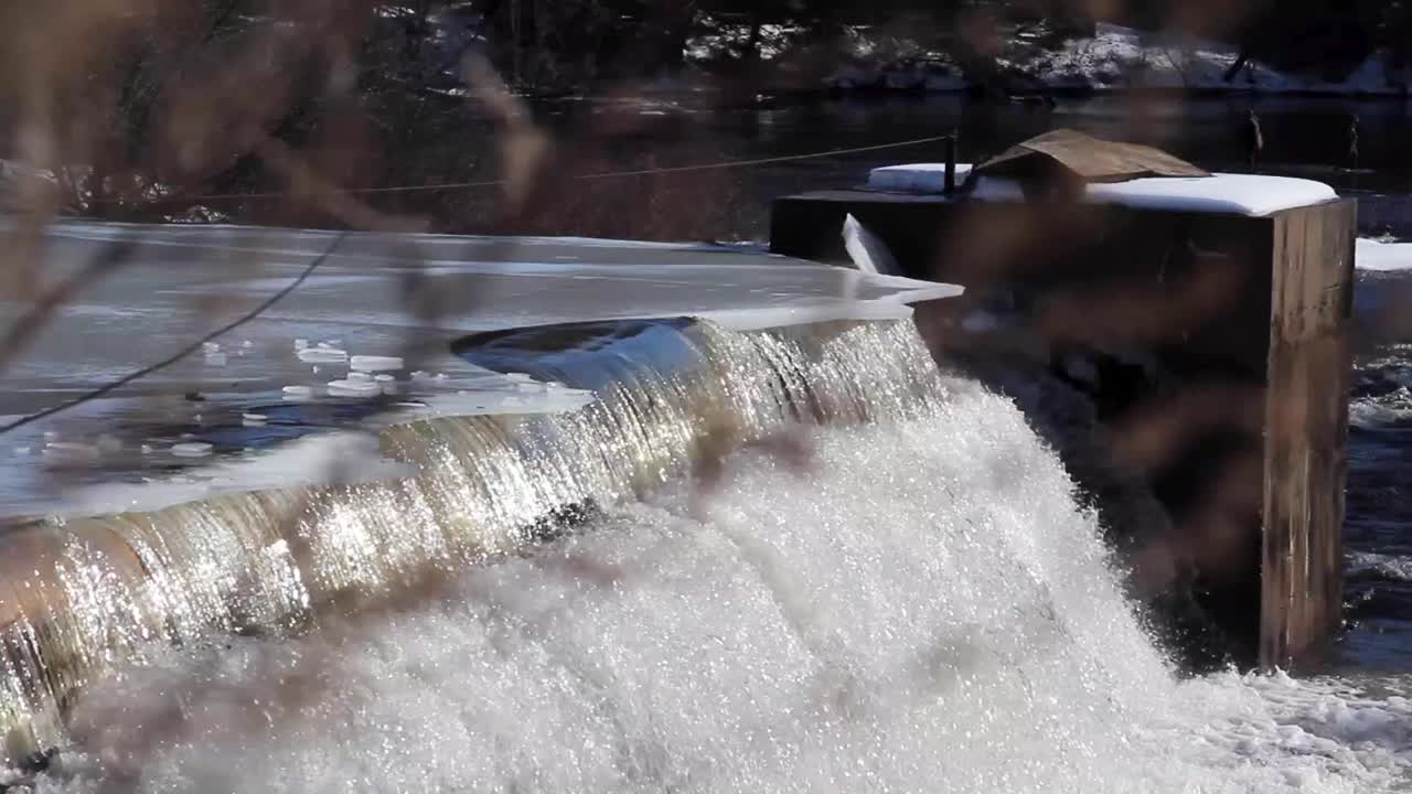 ice hanging over the edge of a frozen dam. Stationary medium shot