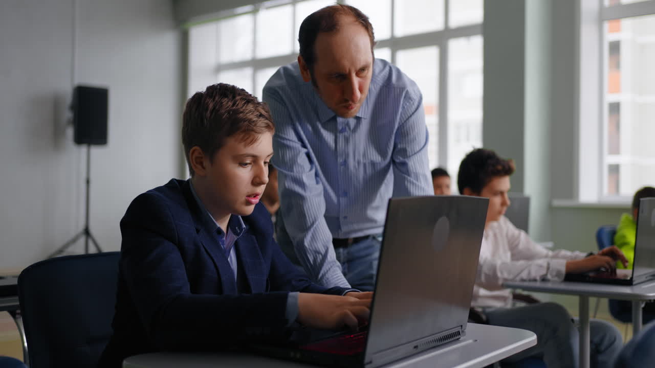 maestro ayudando al estudiante con una computadora portátil en el aula