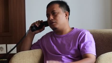 An-Asian-man-calls-his-business-partner-in-a-hotel-room