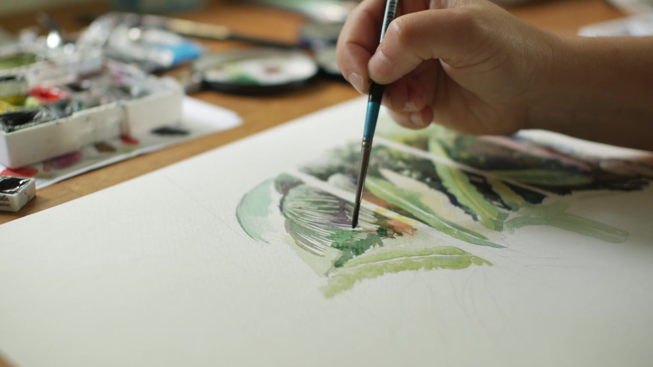 ศิลปินกำลังวาดภาพด้วยสีน้ำบนกระดาษ