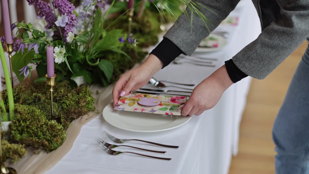 Primer plano de manos de decorador de bodas colocando la oficina en una mesa con tonos púrpura y verde bosque